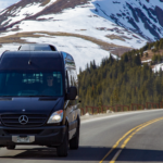 _94E2868 A black sprinter van driving on a road with mountains in the background