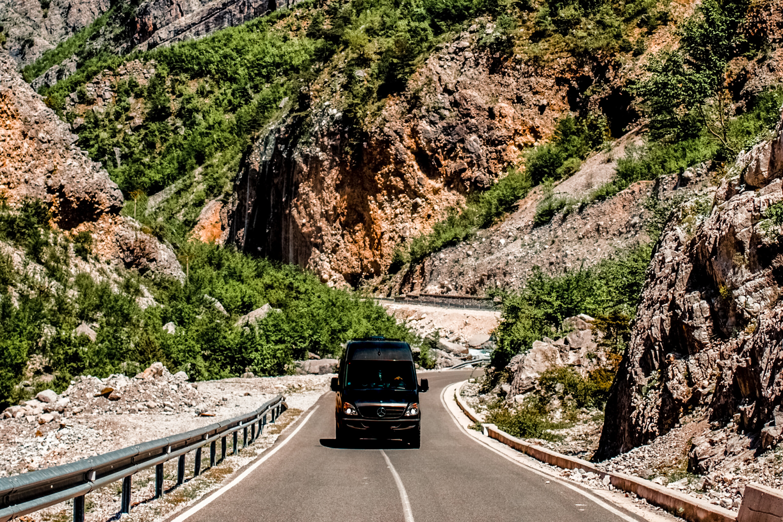 sprinter van on road with mountain in the background A black sprinter van driving on a highway through mountains