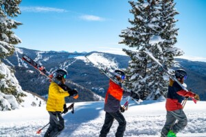 people walking with skis amidst snowy mountains